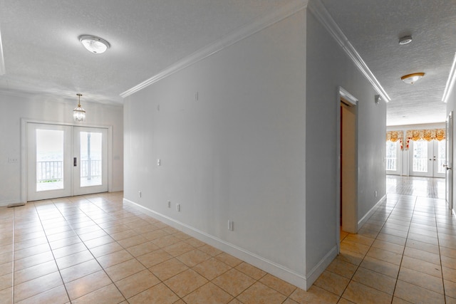 spare room with french doors, light tile patterned flooring, crown molding, and a textured ceiling