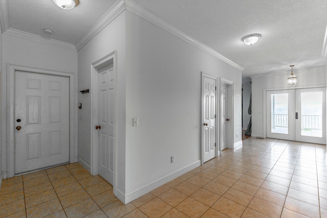 entrance foyer with light tile patterned floors, ornamental molding, a textured ceiling, and french doors