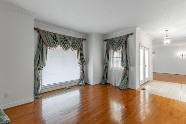 empty room with crown molding, baseboards, and wood finished floors