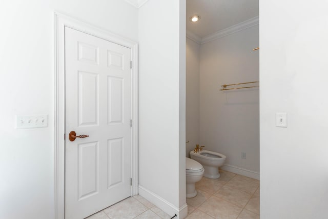 bathroom featuring crown molding, toilet, a bidet, baseboards, and tile patterned floors