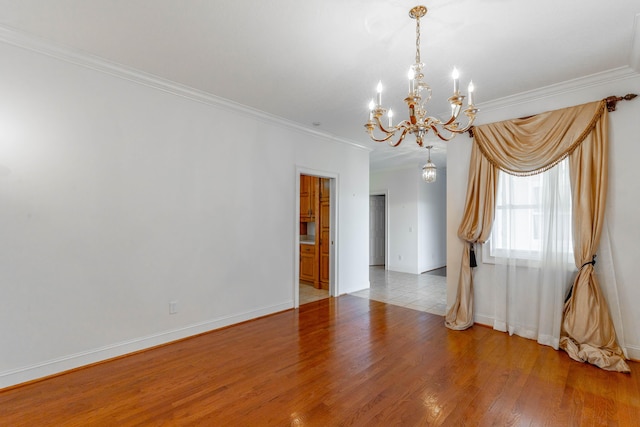 unfurnished room featuring ornamental molding, light wood-type flooring, a notable chandelier, and baseboards