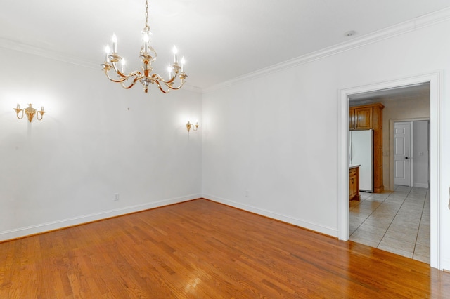 empty room featuring ornamental molding, light wood-style floors, and baseboards