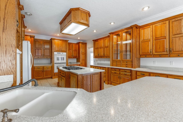 kitchen featuring white appliances, light tile patterned floors, brown cabinetry, light countertops, and a sink