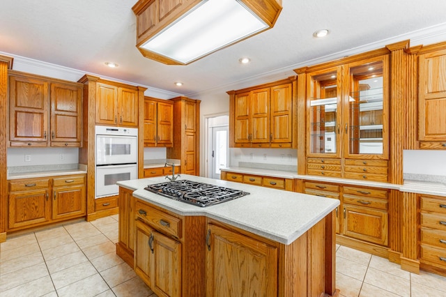 kitchen featuring light tile patterned floors, double oven, gas stovetop, light countertops, and a center island