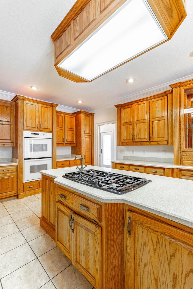 kitchen with brown cabinets, light tile patterned floors, black gas cooktop, double oven, and ornamental molding