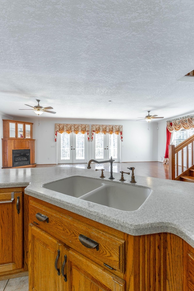 kitchen with brown cabinets, a sink, a textured ceiling, and ceiling fan