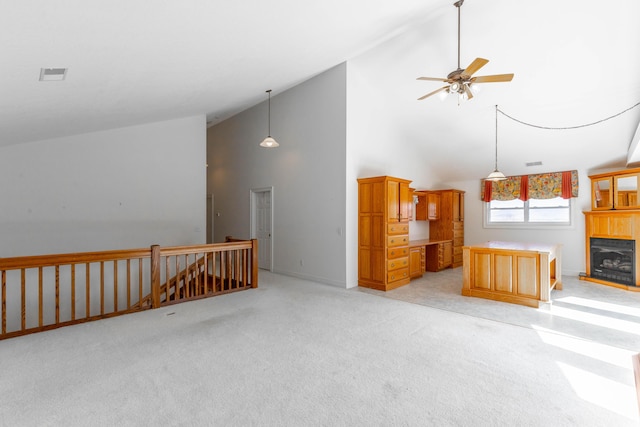 unfurnished living room with high vaulted ceiling, light colored carpet, visible vents, and a fireplace