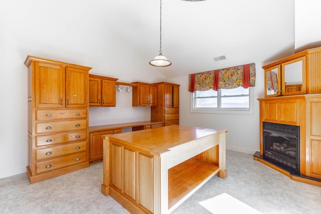 kitchen with a fireplace, visible vents, baseboards, brown cabinets, and decorative light fixtures