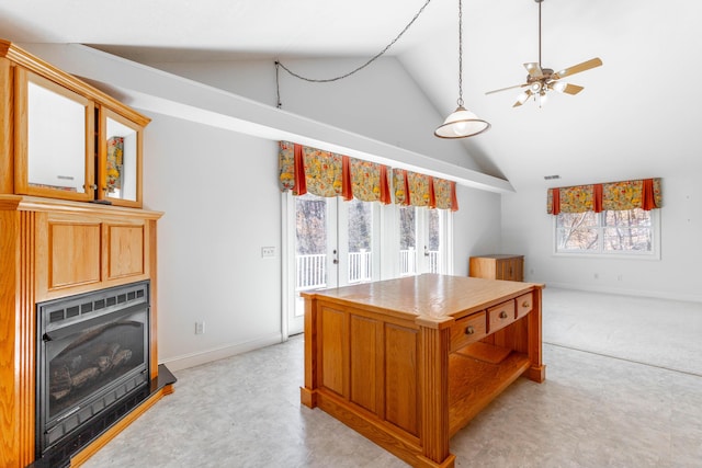 kitchen featuring a ceiling fan, a glass covered fireplace, a kitchen island, high vaulted ceiling, and baseboards