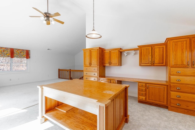 kitchen featuring brown cabinetry, light colored carpet, built in study area, decorative light fixtures, and light countertops