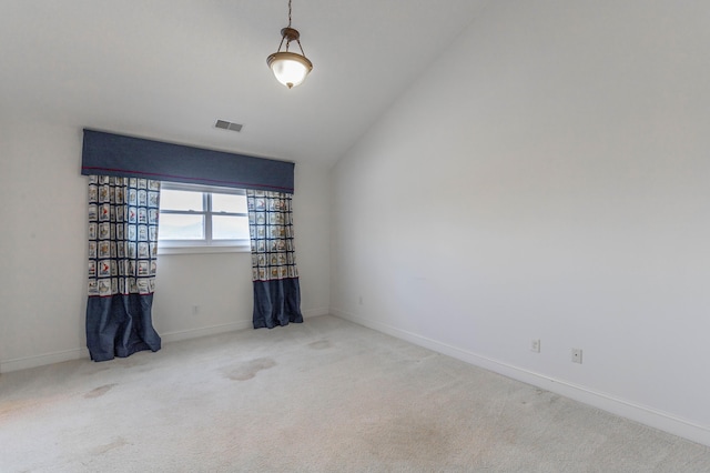 empty room featuring lofted ceiling, carpet floors, visible vents, and baseboards