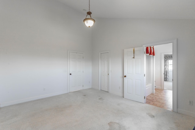 unfurnished room with light carpet, high vaulted ceiling, and baseboards