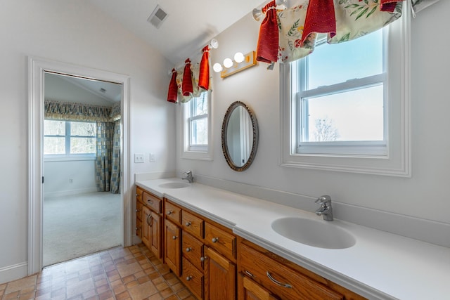 full bathroom with double vanity, visible vents, vaulted ceiling, and a sink