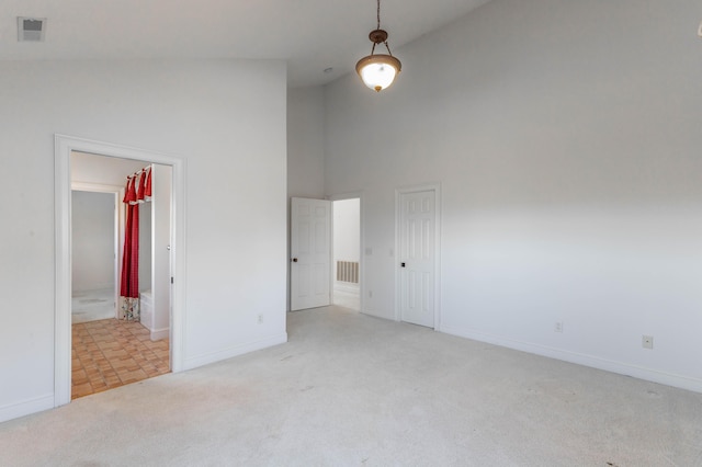 unfurnished room featuring baseboards, high vaulted ceiling, visible vents, and light colored carpet