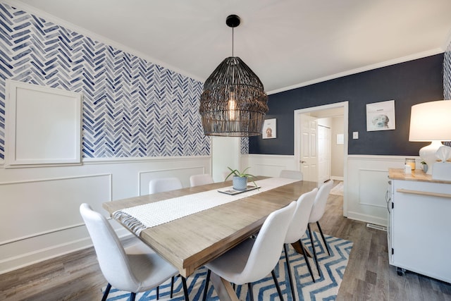 dining room featuring a wainscoted wall, dark wood-style flooring, and ornamental molding