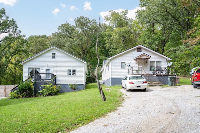 view of front facade featuring a front yard, driveway, and a wooden deck