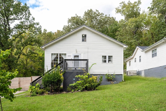 rear view of house featuring a lawn, stairs, and fence