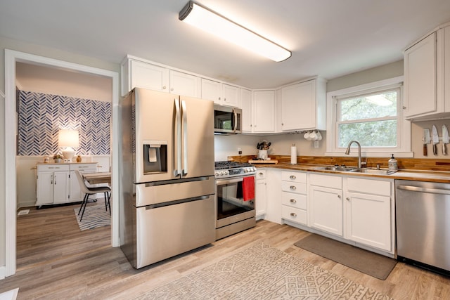 kitchen featuring appliances with stainless steel finishes, white cabinetry, and a sink