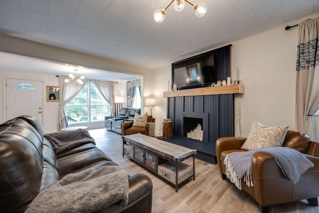 living area with a notable chandelier, a fireplace with raised hearth, and light wood finished floors