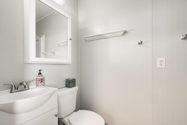 bathroom featuring vanity, tile walls, and toilet