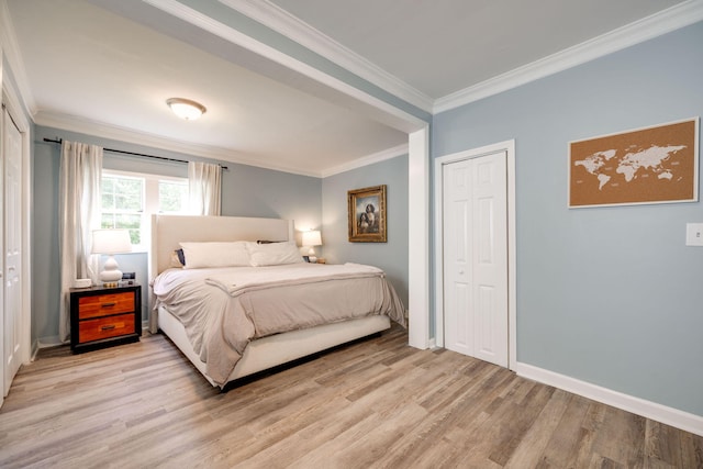 bedroom featuring a closet, baseboards, crown molding, and light wood finished floors