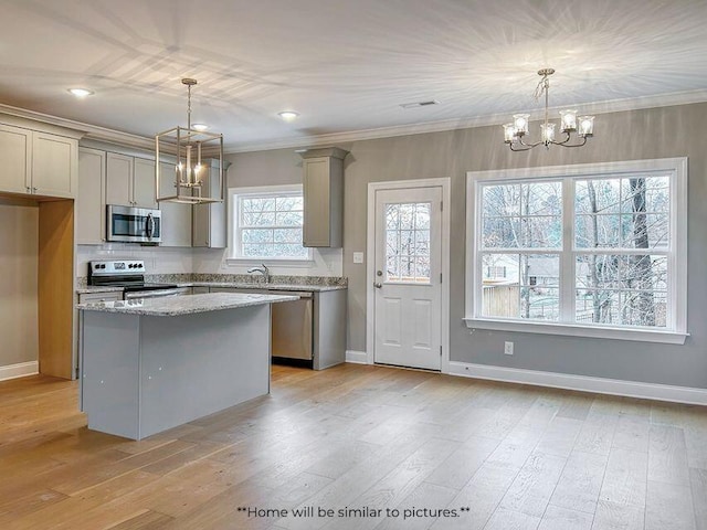 kitchen with stainless steel appliances, crown molding, gray cabinetry, and an inviting chandelier