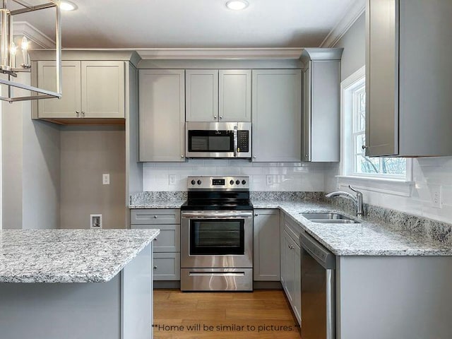 kitchen featuring appliances with stainless steel finishes, decorative backsplash, a sink, and gray cabinetry