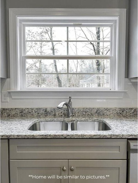 kitchen featuring dishwasher, light stone counters, and a sink