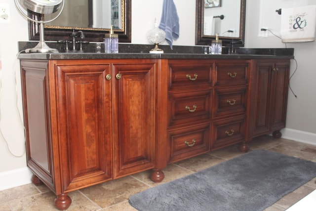 bathroom with double vanity, a sink, and baseboards