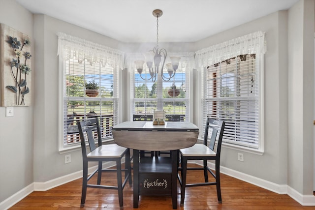 dining space featuring baseboards, wood finished floors, and an inviting chandelier