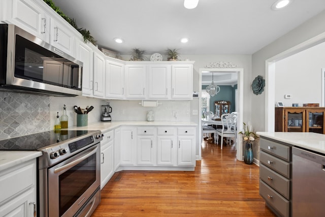 kitchen with white cabinetry, light wood-style flooring, appliances with stainless steel finishes, and light countertops