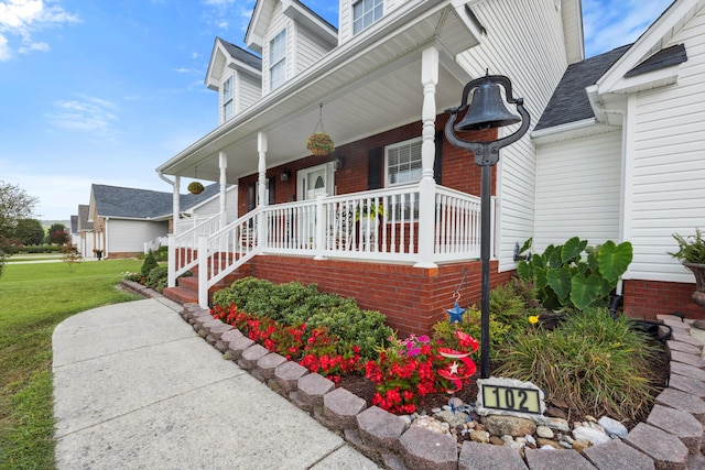 entrance to property featuring a porch and a yard