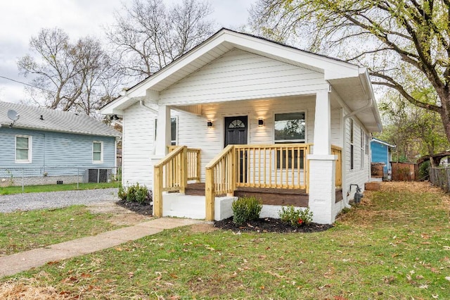 view of front facade with gravel driveway, covered porch, fence, cooling unit, and a front yard