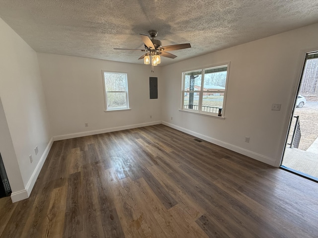 empty room featuring dark wood-style floors, visible vents, a ceiling fan, a textured ceiling, and baseboards