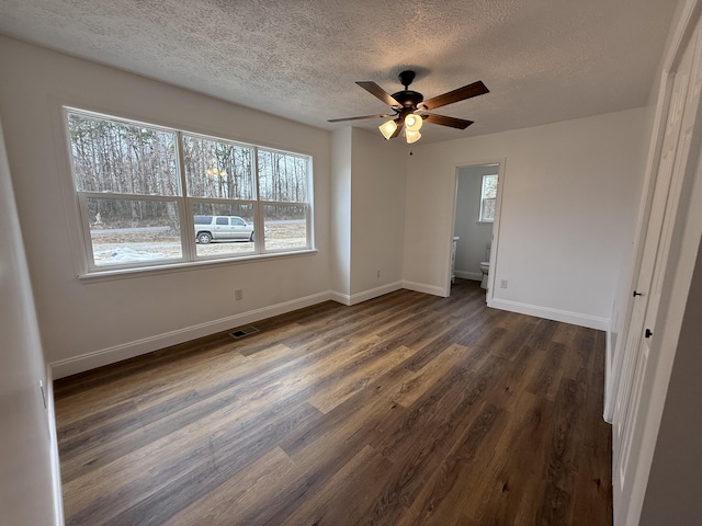 unfurnished bedroom with baseboards, multiple windows, visible vents, and dark wood finished floors