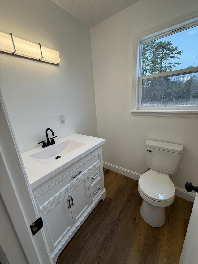 bathroom with vanity, wood finished floors, toilet, and baseboards