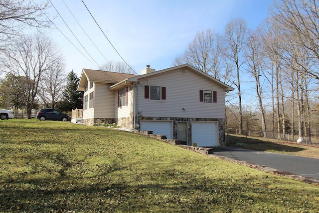 view of side of home featuring a garage, stone siding, a chimney, and aphalt driveway