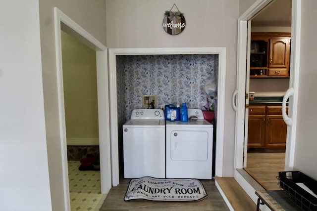 clothes washing area with washing machine and dryer, laundry area, and wood finished floors