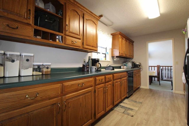 kitchen featuring black dishwasher, light wood-style flooring, brown cabinets, open shelves, and a sink