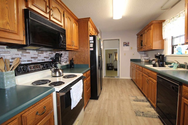 kitchen featuring black appliances, light wood-style floors, a sink, and brown cabinets