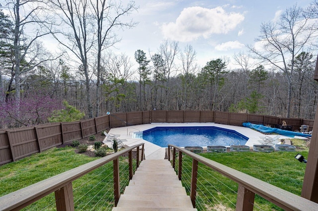 view of pool with a forest view, a yard, a fenced in pool, and a fenced backyard