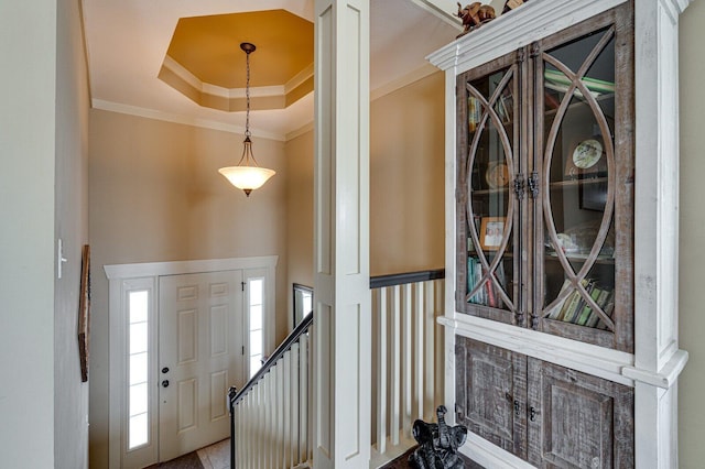 entrance foyer with a raised ceiling and ornamental molding