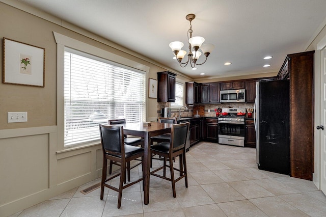 dining area with a notable chandelier, recessed lighting, wainscoting, a decorative wall, and light tile patterned floors