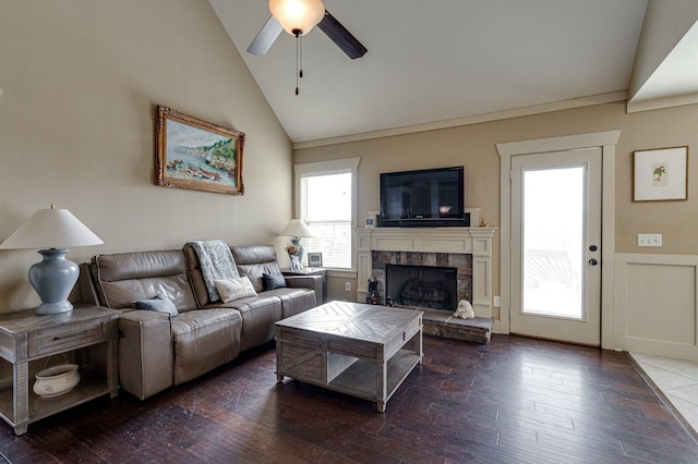 living room with wainscoting, a fireplace with raised hearth, ceiling fan, and hardwood / wood-style floors