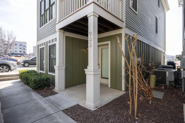 doorway to property featuring central air condition unit, a balcony, and board and batten siding