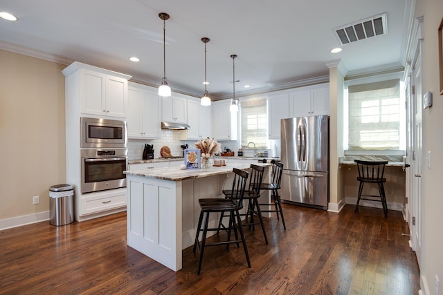 kitchen with stainless steel appliances, a breakfast bar area, visible vents, and crown molding