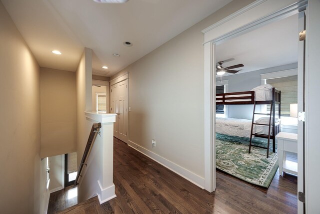 hall featuring recessed lighting, dark wood-style flooring, baseboards, and an upstairs landing