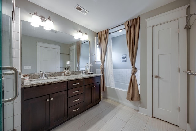 full bath featuring double vanity, visible vents, bath / shower combo with glass door, and a sink