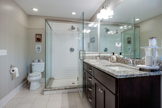 bathroom featuring toilet, a stall shower, baseboards, and a sink