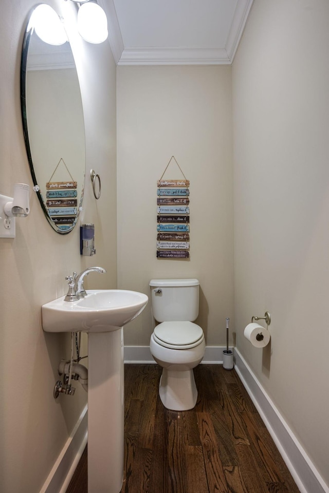 bathroom with toilet, a sink, wood finished floors, baseboards, and crown molding